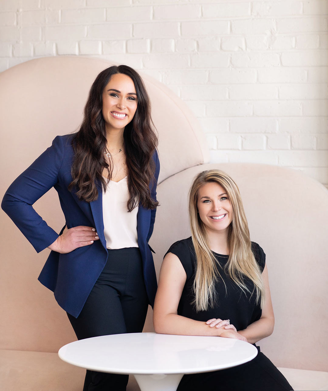 The Life and Liberty Law Office team duo, Sarah Schielke and Madie Baskin are seated in front of a modern background. 